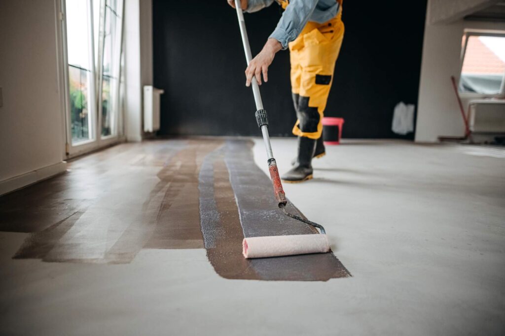 A worker painting a concrete floor in St. Augustine, FL