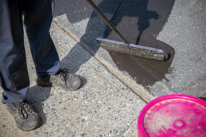Brushing black coating on textured pavement by Custom Floor Coating