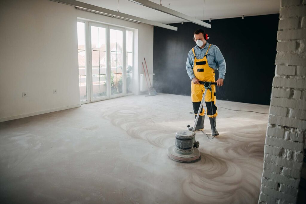 Worker polishing concrete floor in a dusty indoor space in Jacksonville